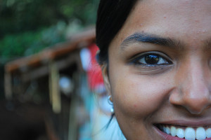 Photo of a woman's face off-center to the camera. She is smiling and her teeth are bright white.